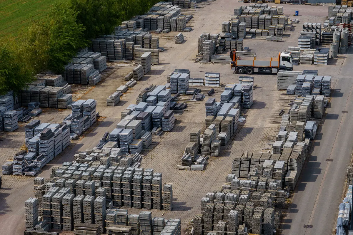 A stock yard seen from above, pallets of concrete blocks in rows and a flatbed lorry between them